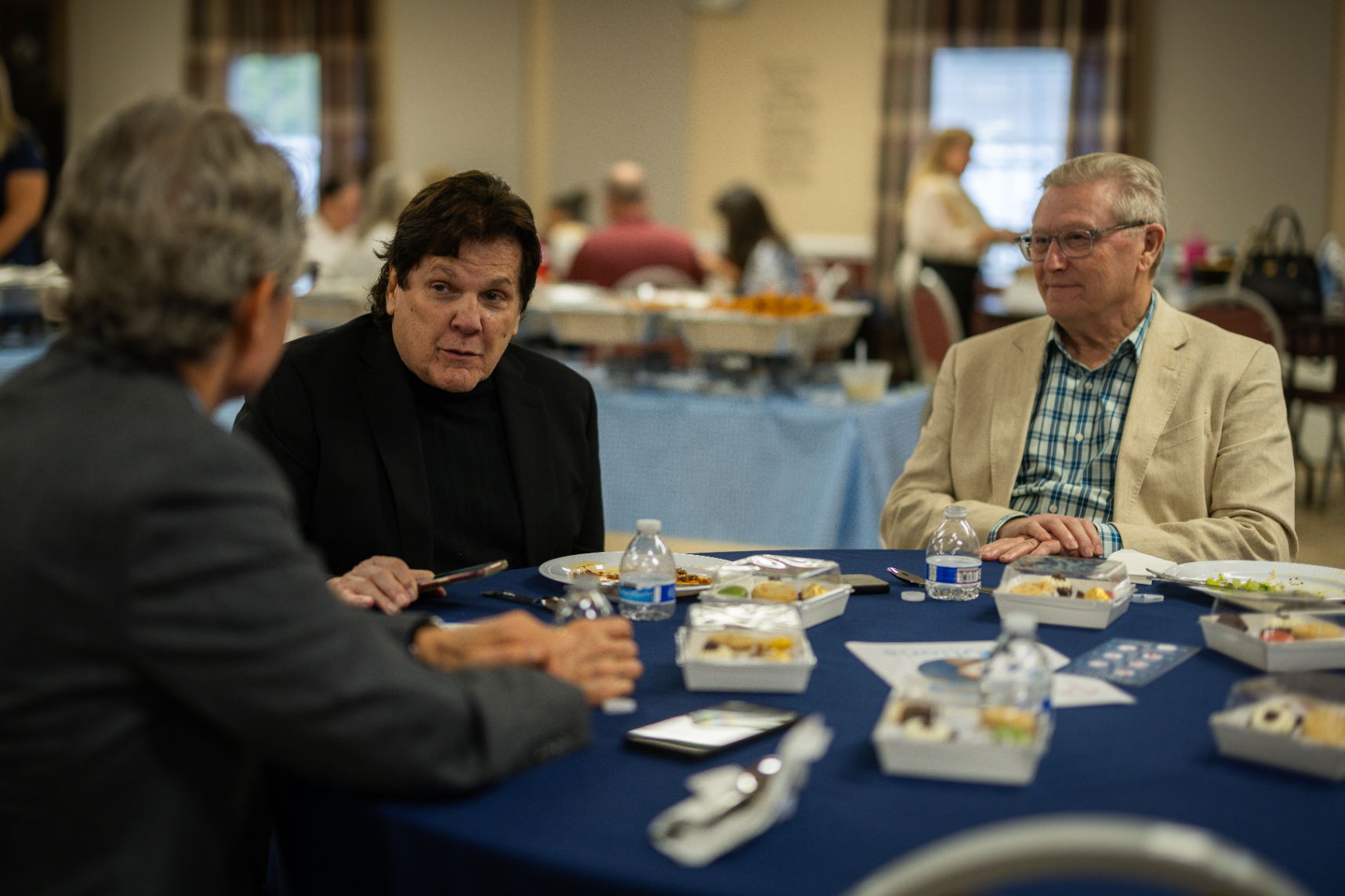 A group of people are sitting at a table talking to each other.