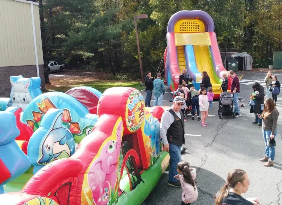 A group of people are standing around a bouncy house.