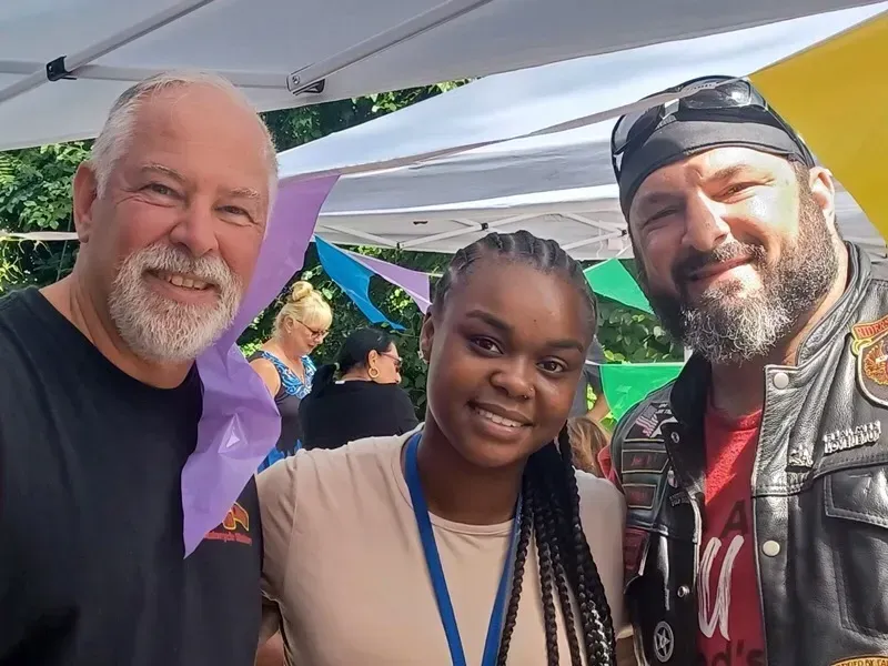 Two men and a woman are posing for a picture in front of a tent.