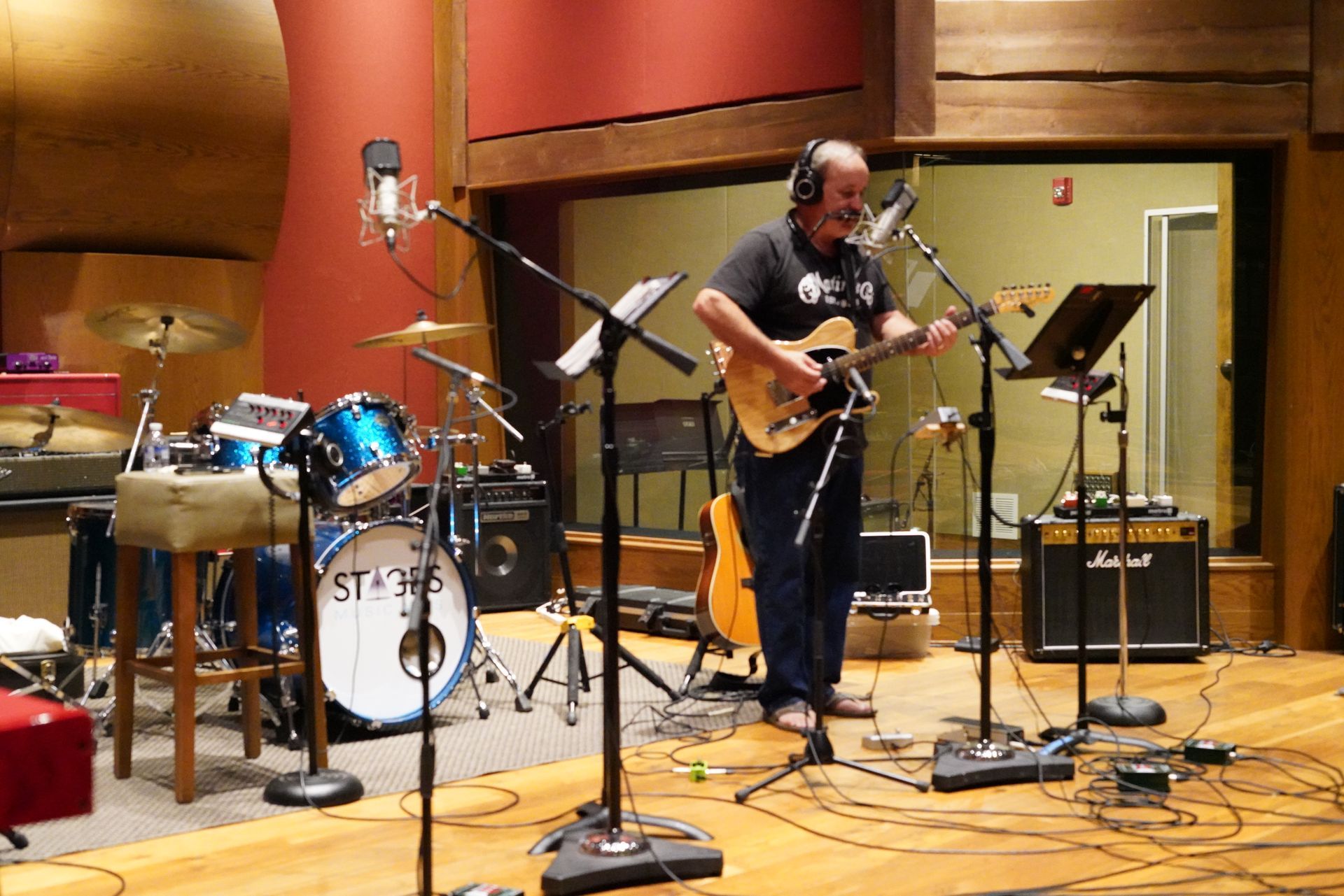 A man is playing a guitar in a recording studio