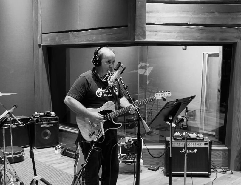 A man is singing into a microphone while playing a guitar