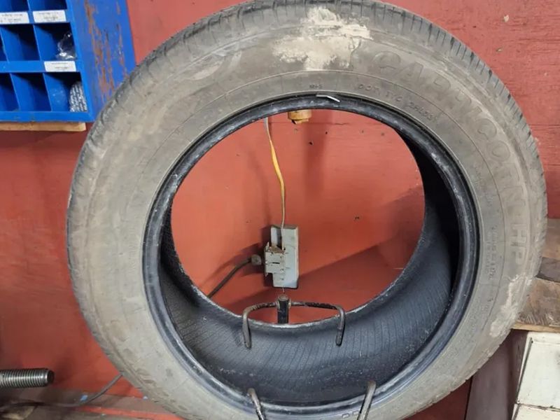 A dirty tire is sitting on a metal stand