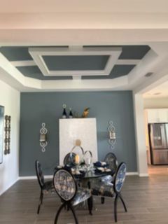 Paint supplies: paint roller, brush, and tray in shades of blue on a painted blue surface.