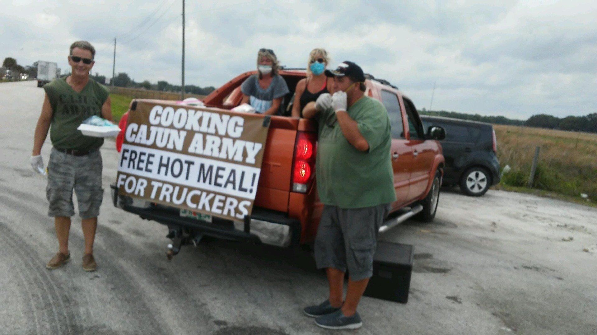 A truck with a sign that says cooking cajun army free hot meal for truckers