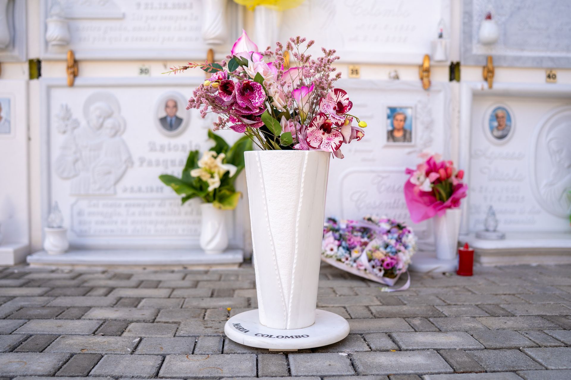 Vaso bianco con fiori rosa davanti alle cripte di marmo.