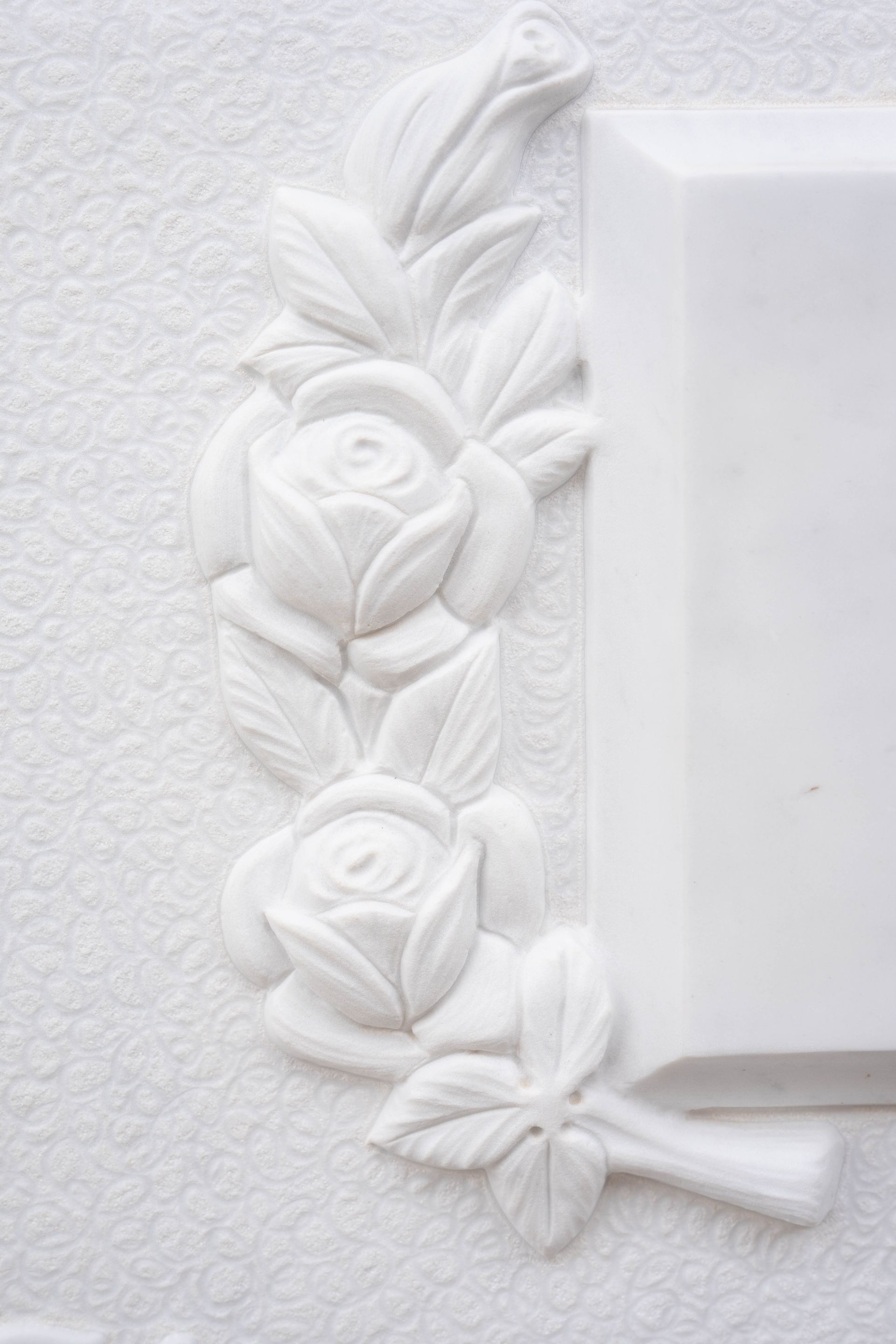 Un muro bianco con un intaglio di rose e foglie.