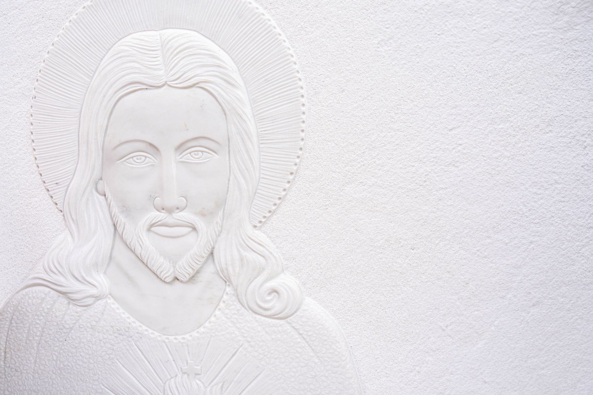 Una statua bianca di Gesù su un muro bianco.