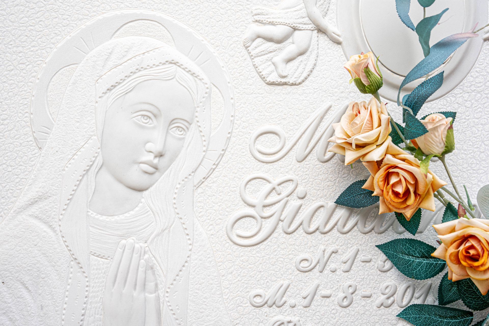 Una lapide con una statua di donna e delle rose sopra.