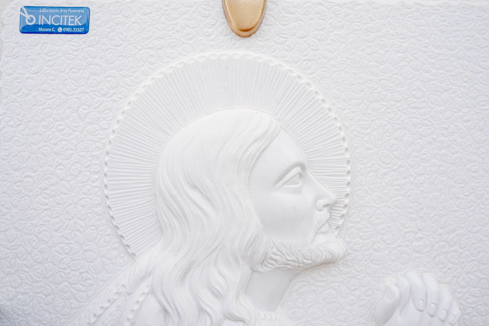 Una statua bianca di Gesù è su un muro bianco.