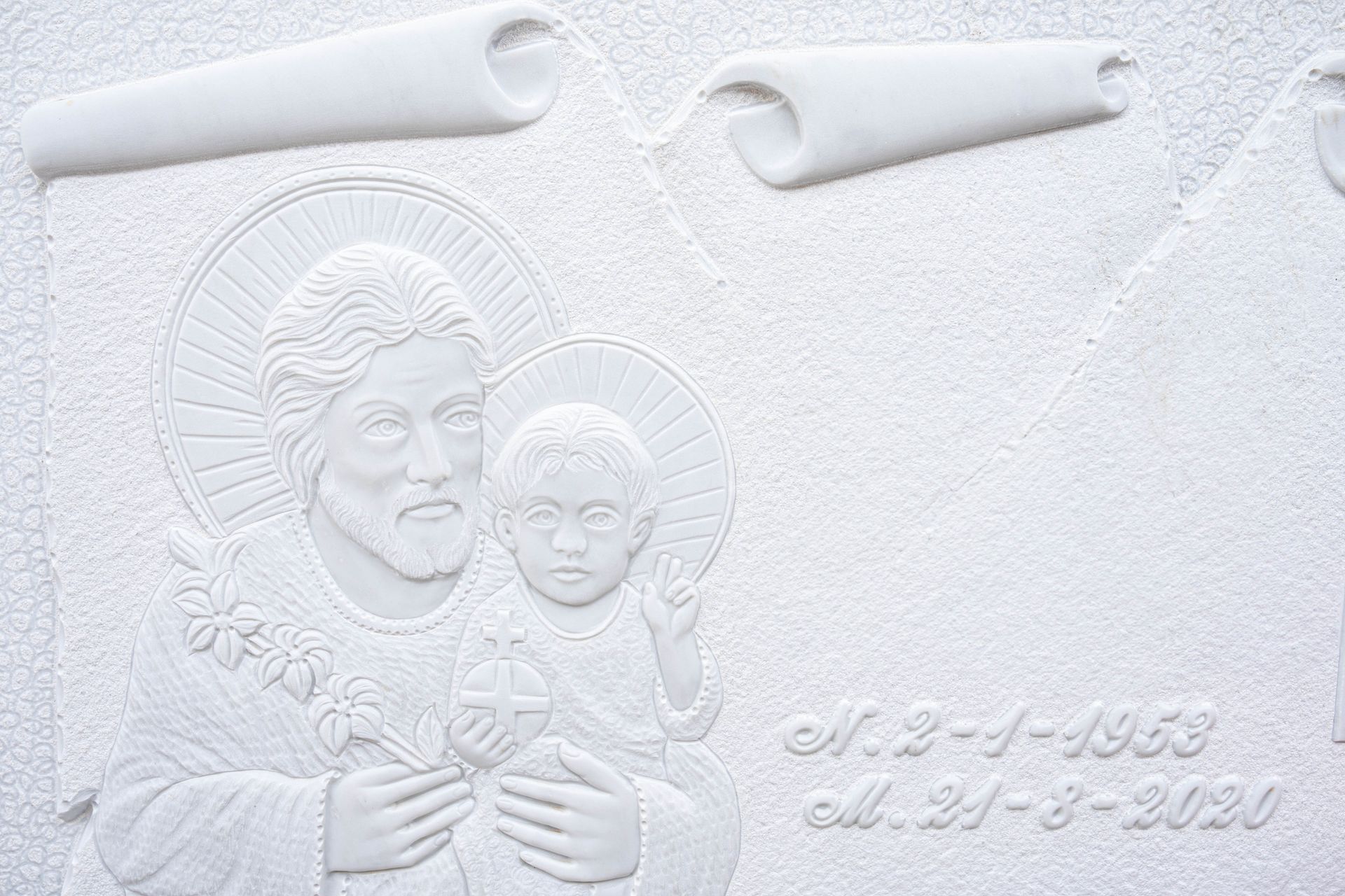 Su un muro bianco c'è una statua di Gesù che tiene in braccio un bambino.