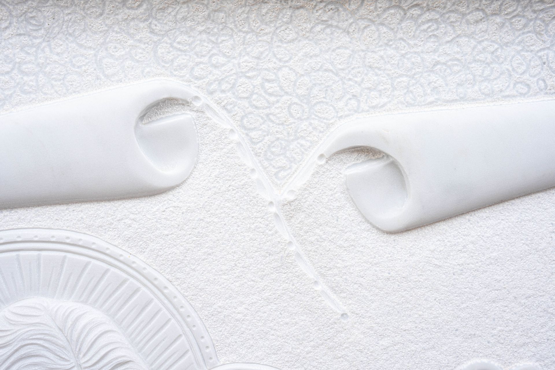 Un primo piano di una scultura bianca su un muro.