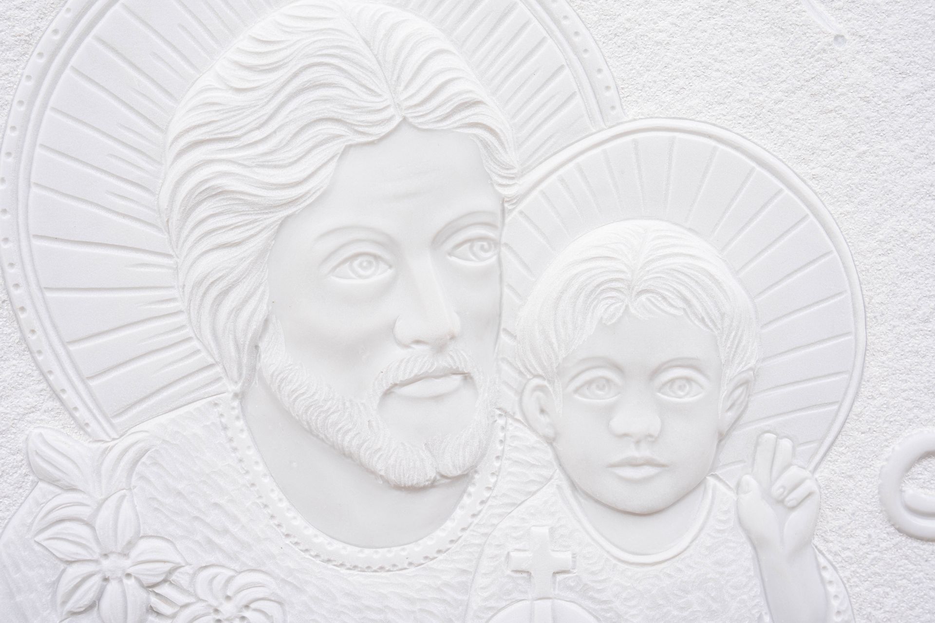 Una statua bianca di Gesù e di Gesù bambino su un muro.