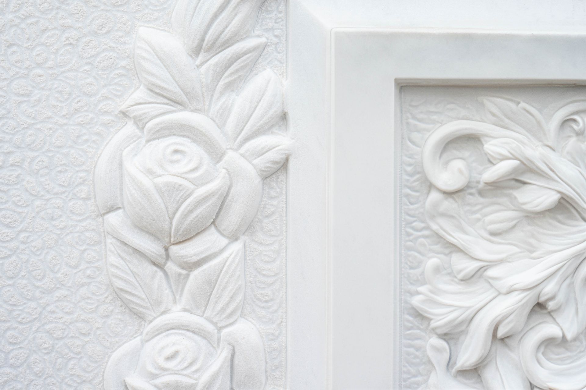 Primo piano di un'incisione bianca su un muro con rose e foglie.