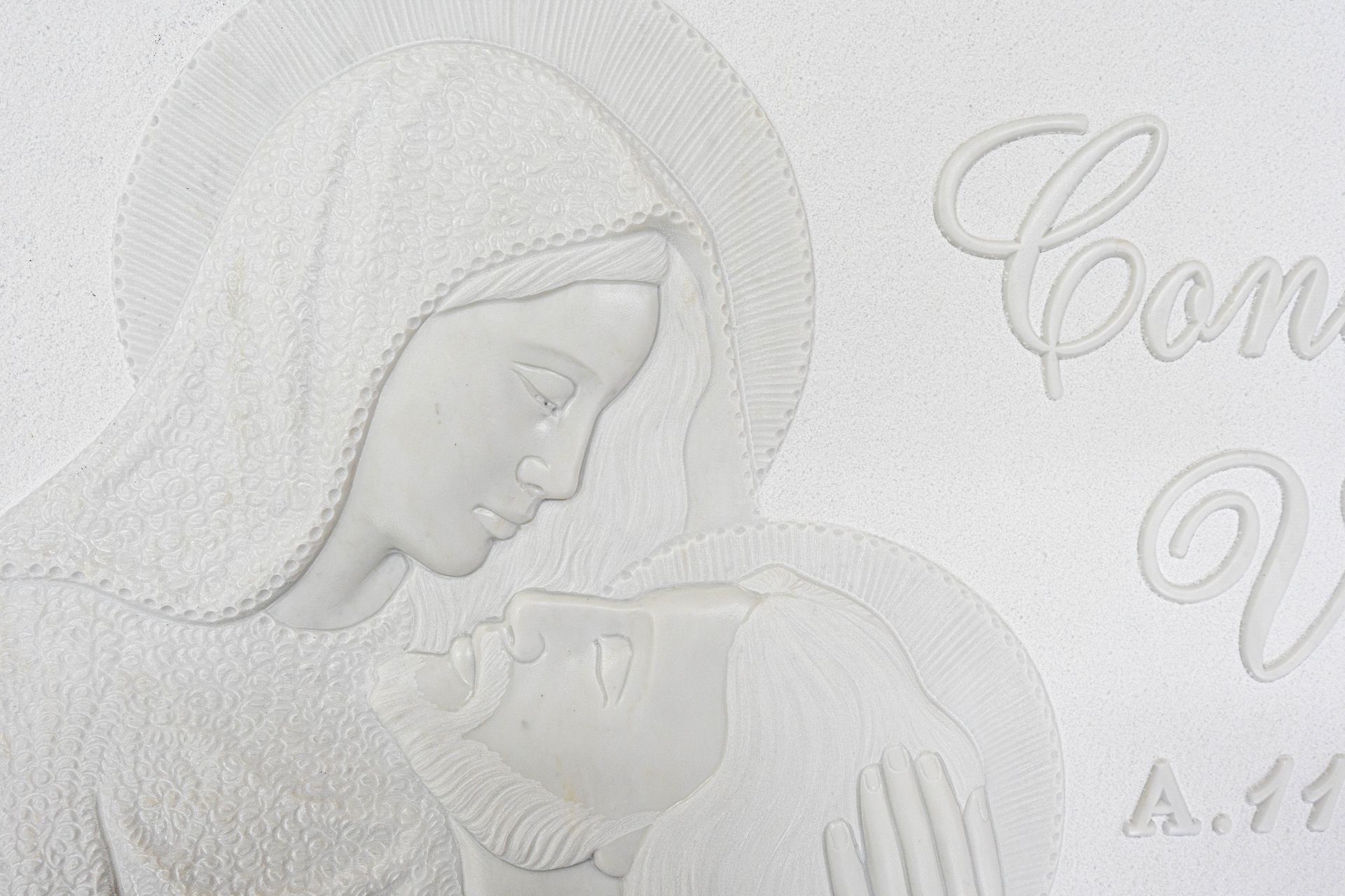 Una statua bianca di una donna che tiene in braccio un bambino addormentato.