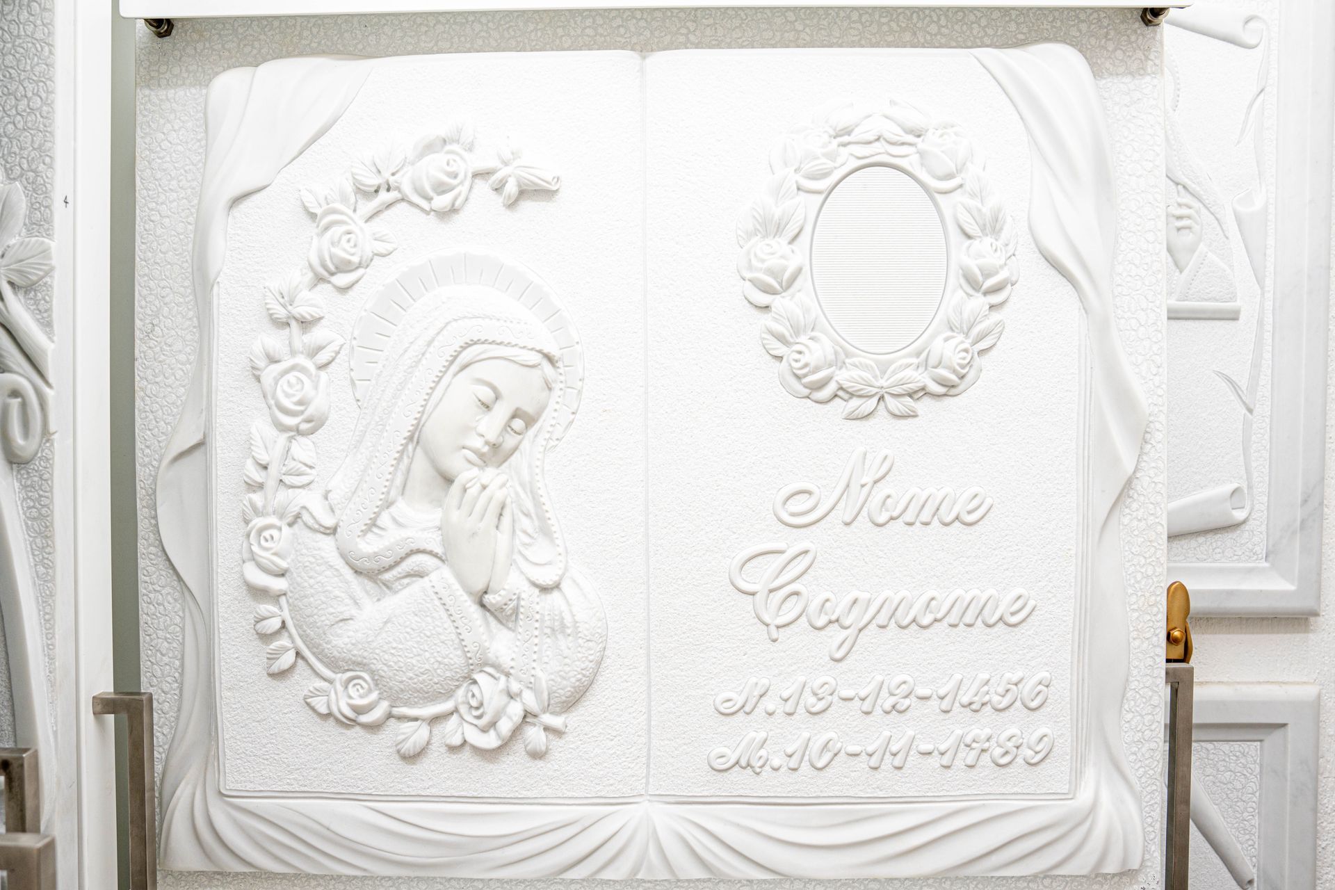 Una targa di marmo bianco con la statua di una donna che tiene in braccio un bambino.