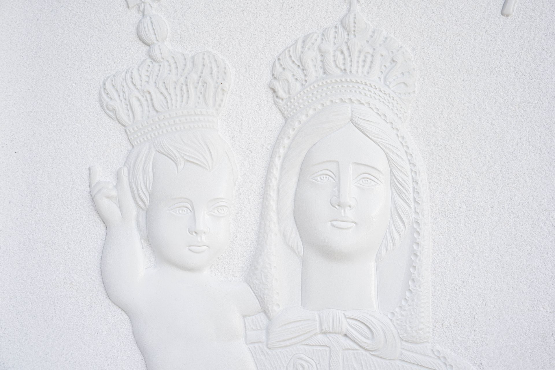 Una statua bianca di una donna che tiene in braccio un bambino e ha una corona in testa.
