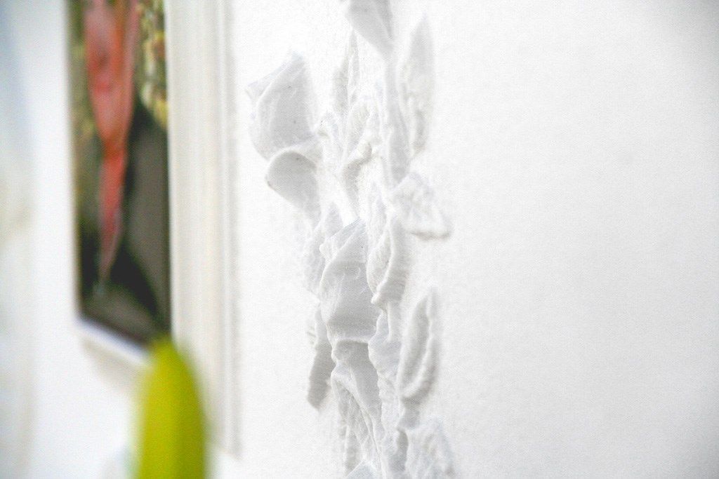 Un muro bianco con una scultura di fiori.