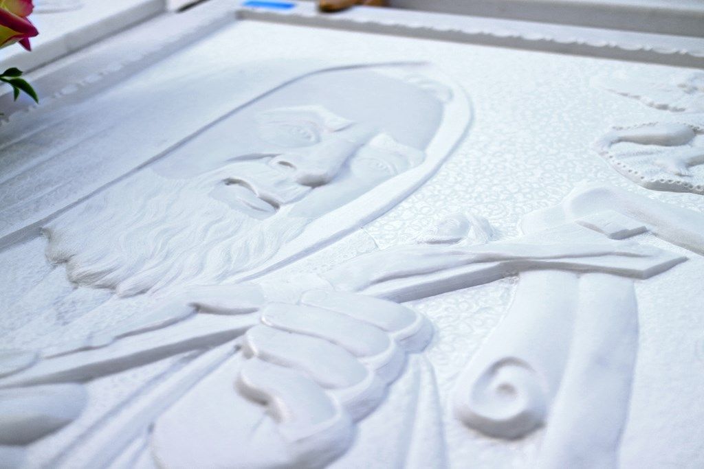 Una statua di un uomo con la barba è scolpita su una superficie bianca