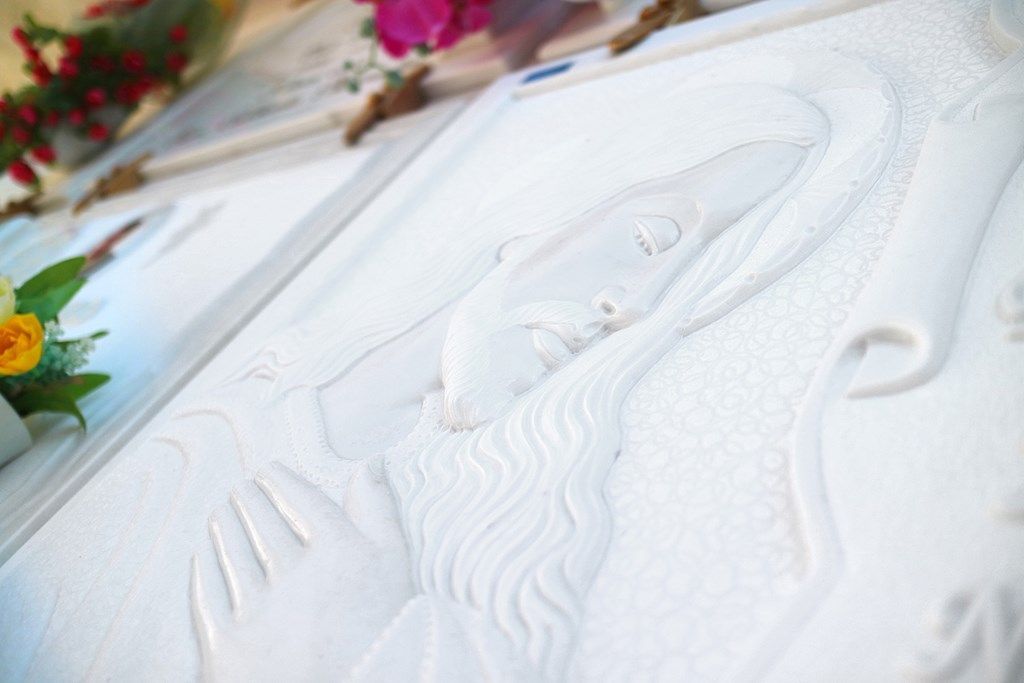 Una statua di un uomo con la barba è scolpita su una superficie bianca.