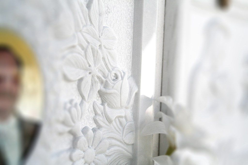 Un uomo in giacca e cravatta è in piedi davanti a una tenda bianca decorata con dei fiori.