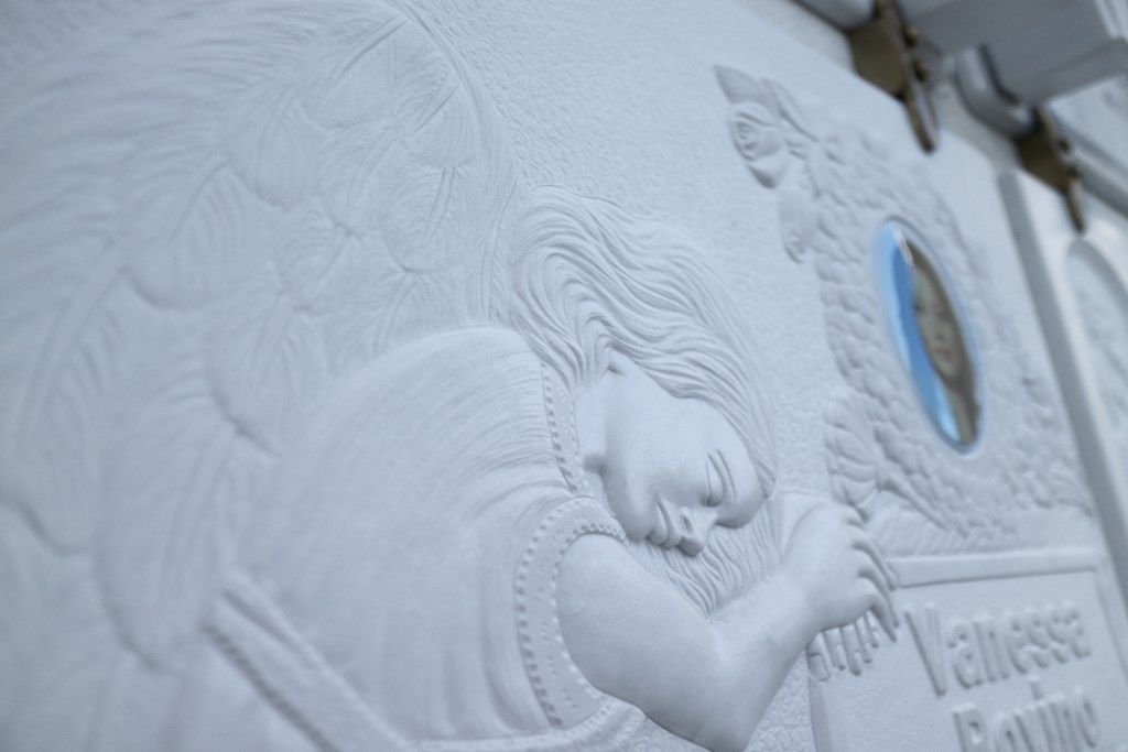 Un primo piano di una statua di una donna addormentata su un muro.