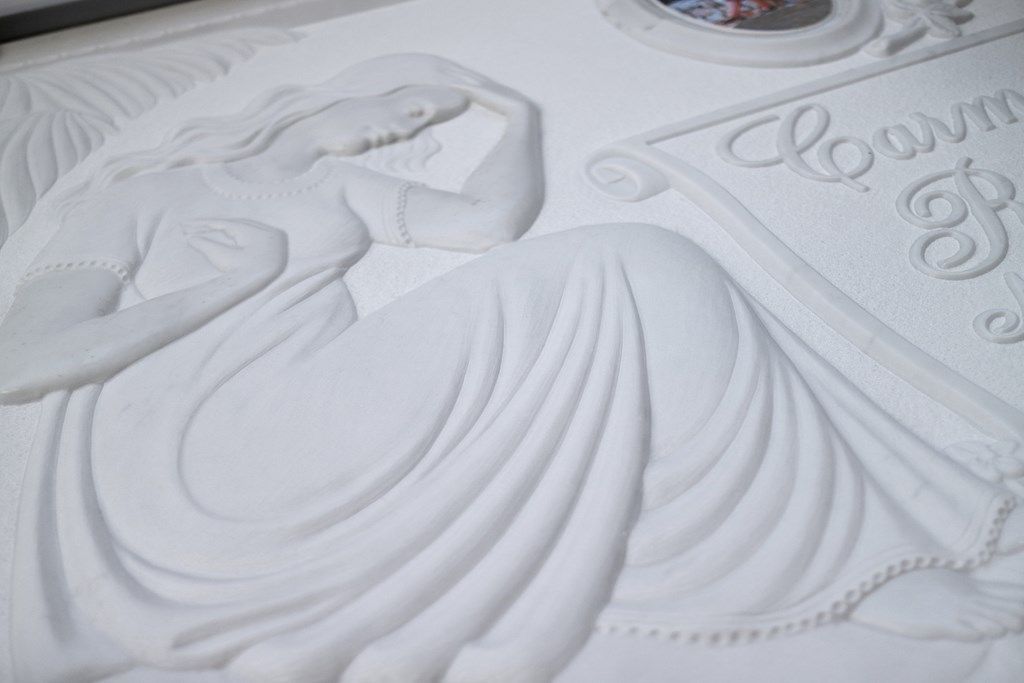 Un primo piano di una statua di una donna in abito bianco su una superficie bianca.