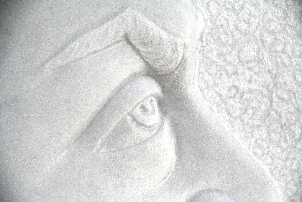 Un primo piano di una statua raffigurante l'occhio di un uomo su una superficie bianca.