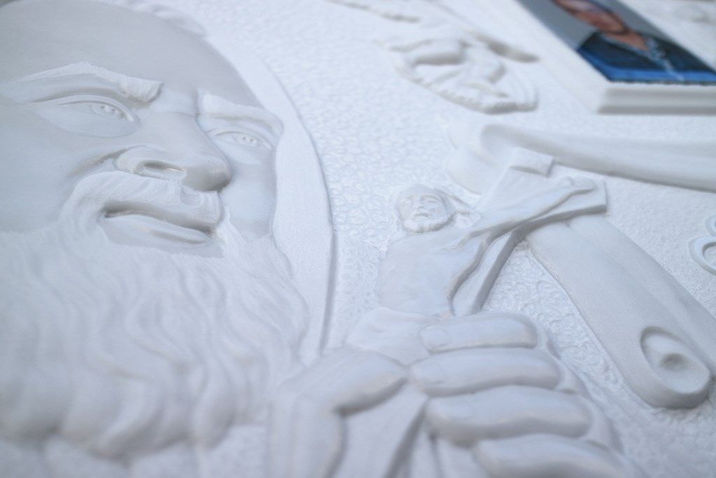 Primo piano della statua di un uomo con la barba che regge una croce.