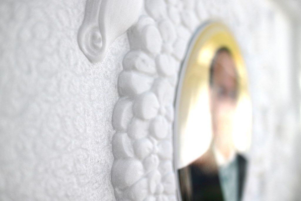 Su una parete bianca è appesa la foto di un uomo in giacca e cravatta.