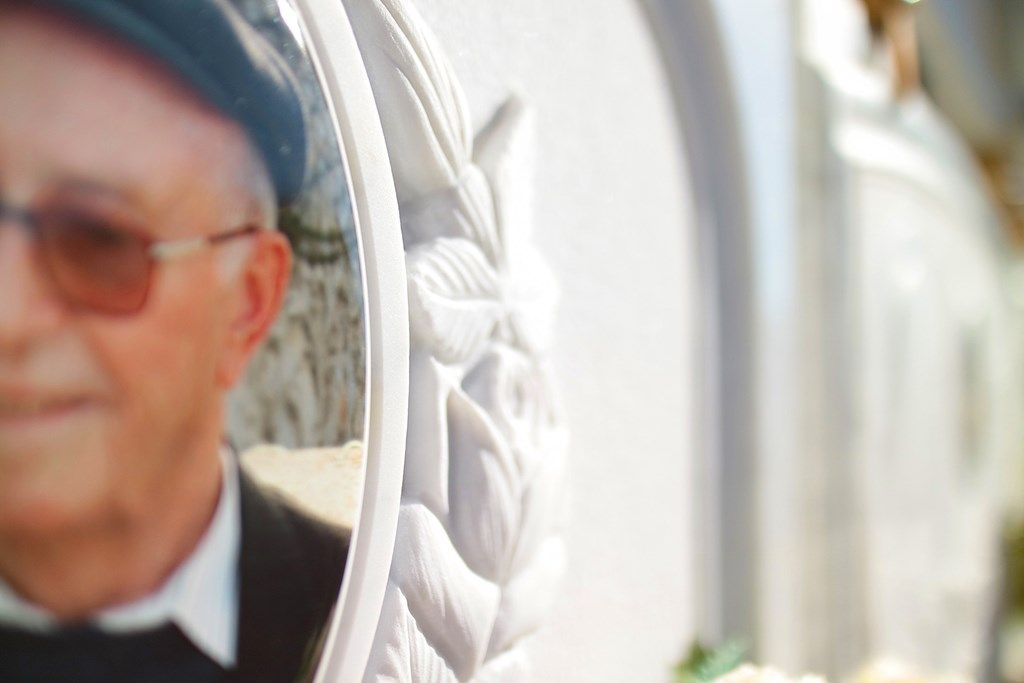 Un uomo con cappello e occhiali da sole è in piedi davanti a una tomba.