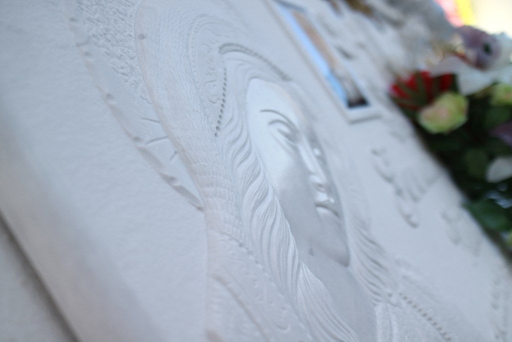 Un primo piano di una scultura raffigurante un volto di donna su un muro.