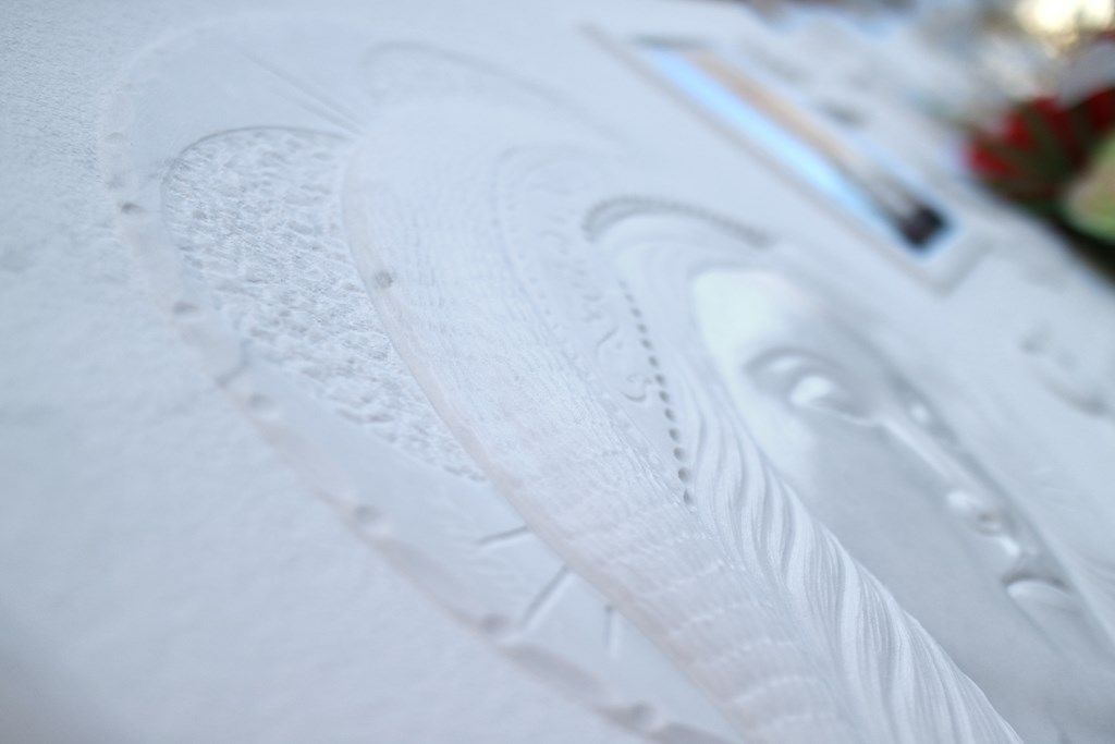 Un primo piano di una piuma bianca su una superficie bianca.