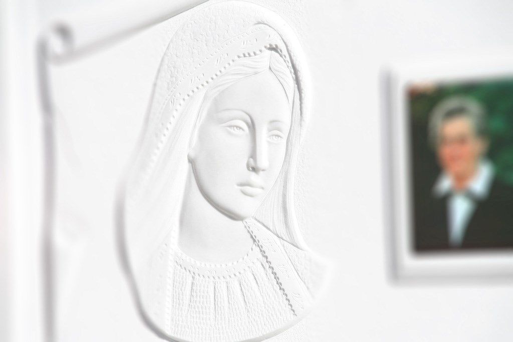 Una statua bianca di una donna è appesa a una parete accanto alla foto di un uomo.