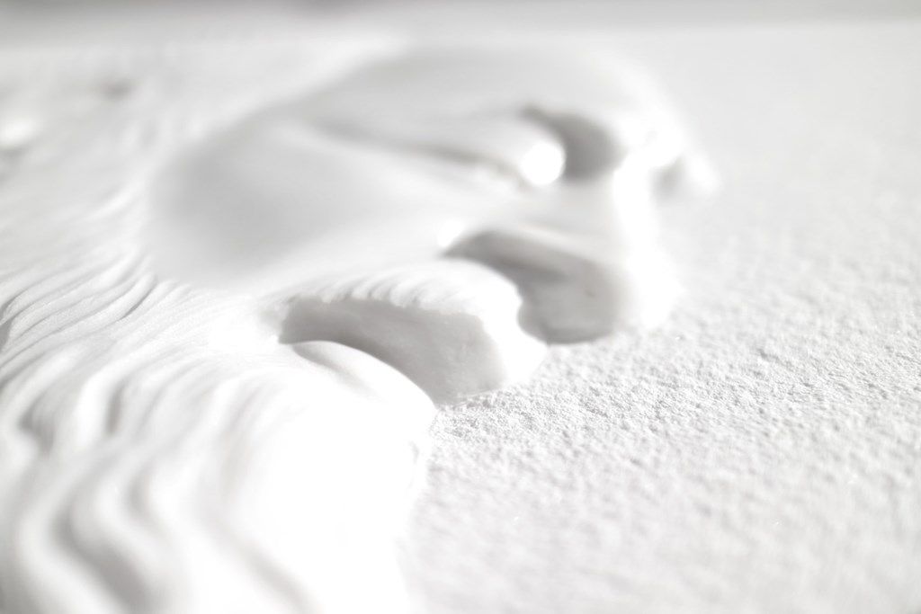 Un primo piano di una statua bianca raffigurante il volto di un uomo su una superficie bianca.