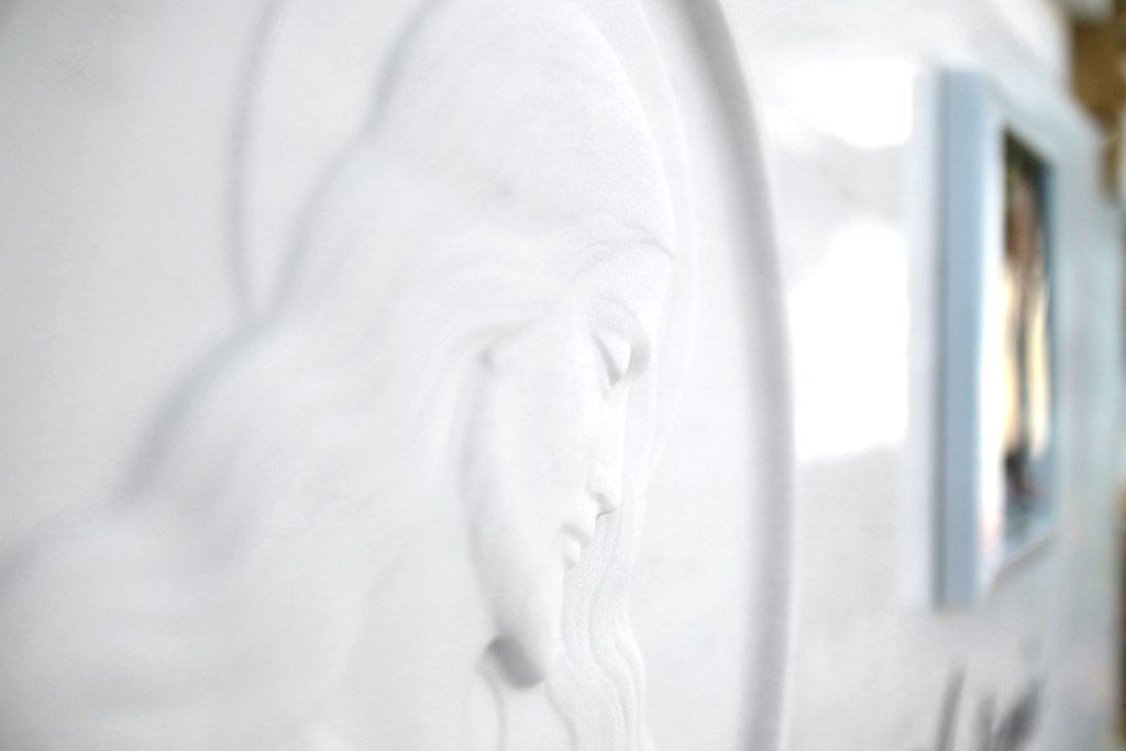 Un primo piano di un muro bianco con un quadro sopra.