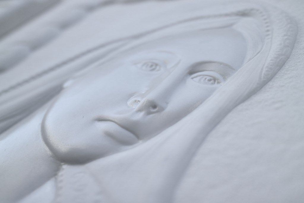 Un primo piano di una statua raffigurante il volto di una donna su una superficie bianca.