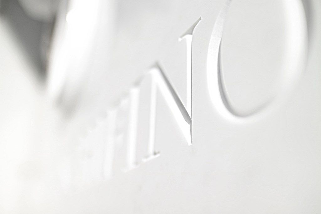 La parola vino è incisa su una superficie bianca.