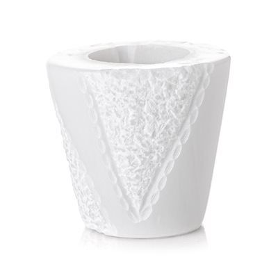 Un vaso bianco con un motivo in pizzo su uno sfondo bianco.