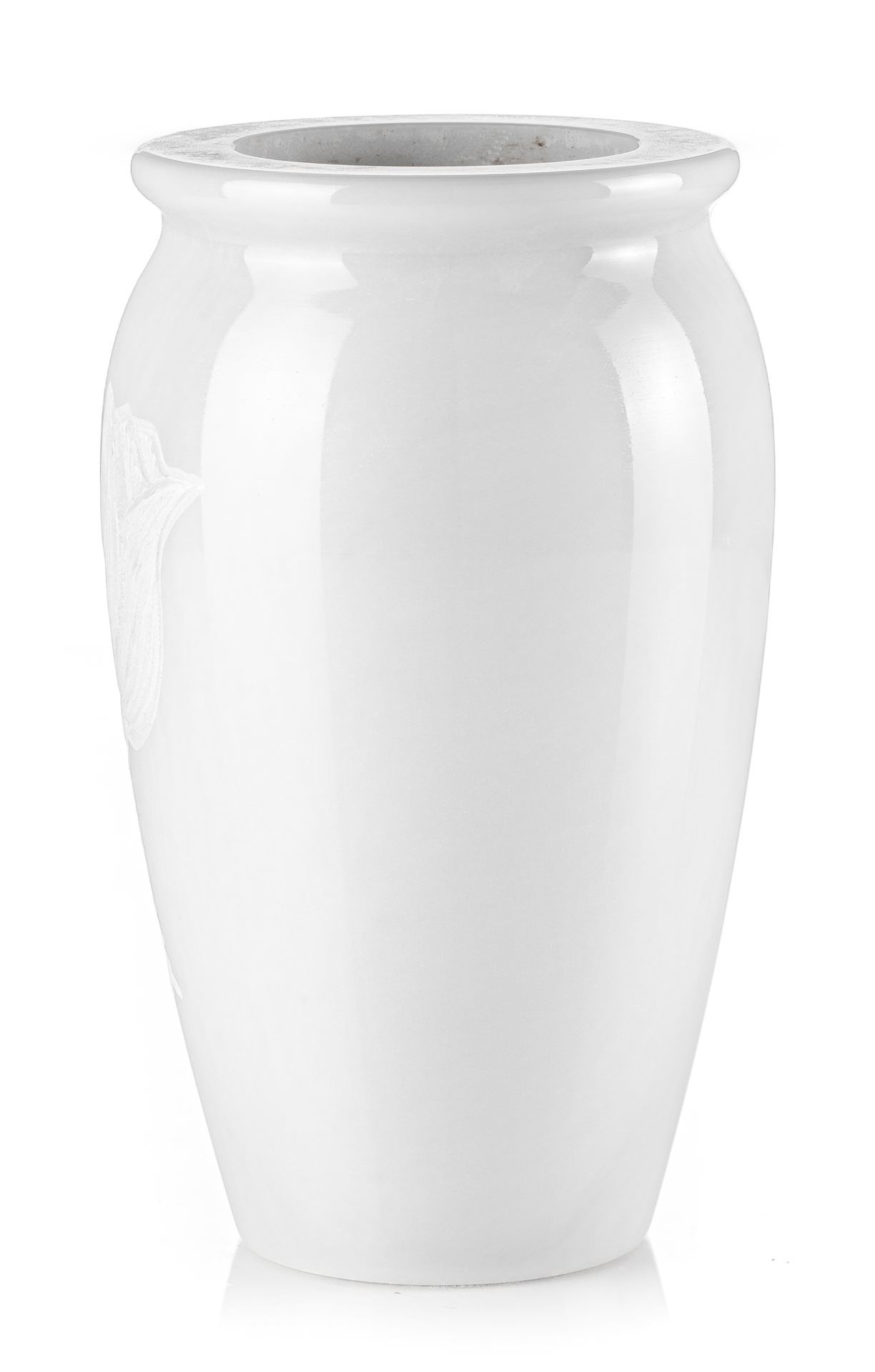 Un vaso bianco è appoggiato su una superficie bianca.