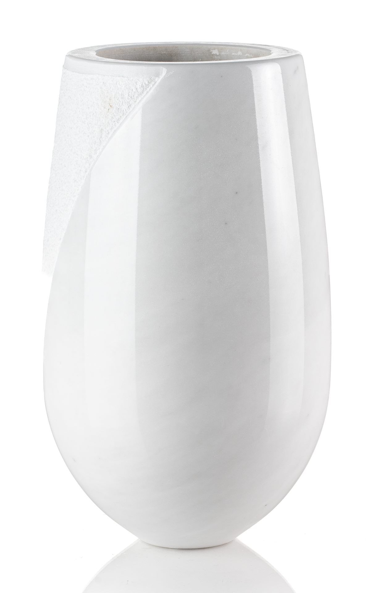 Un vaso bianco è appoggiato su una superficie bianca.