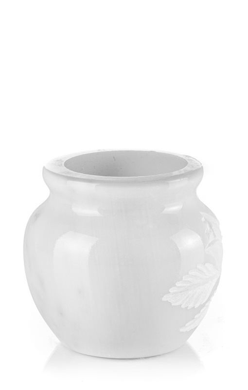 Un vaso bianco è appoggiato su una superficie bianca.