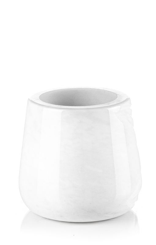 Un vaso bianco è appoggiato su una superficie bianca.