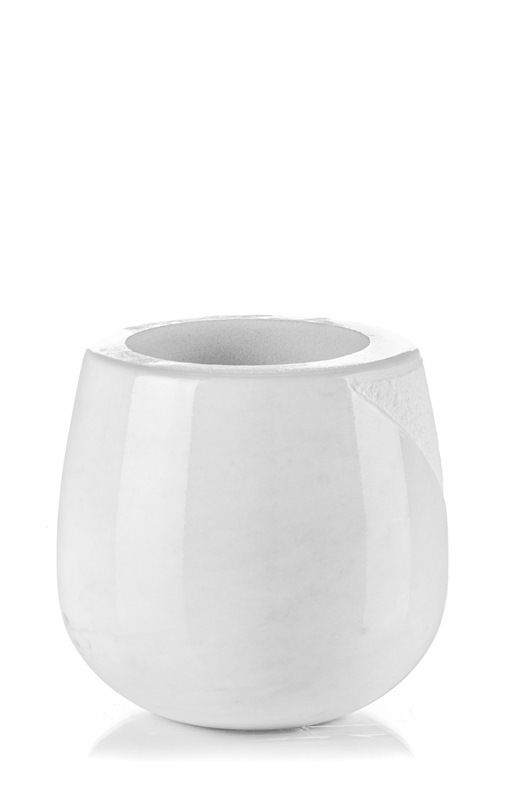 Un vaso bianco è appoggiato su una superficie bianca.