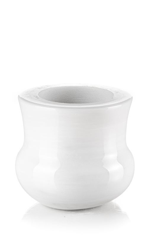 Un vaso bianco è appoggiato su una superficie bianca.