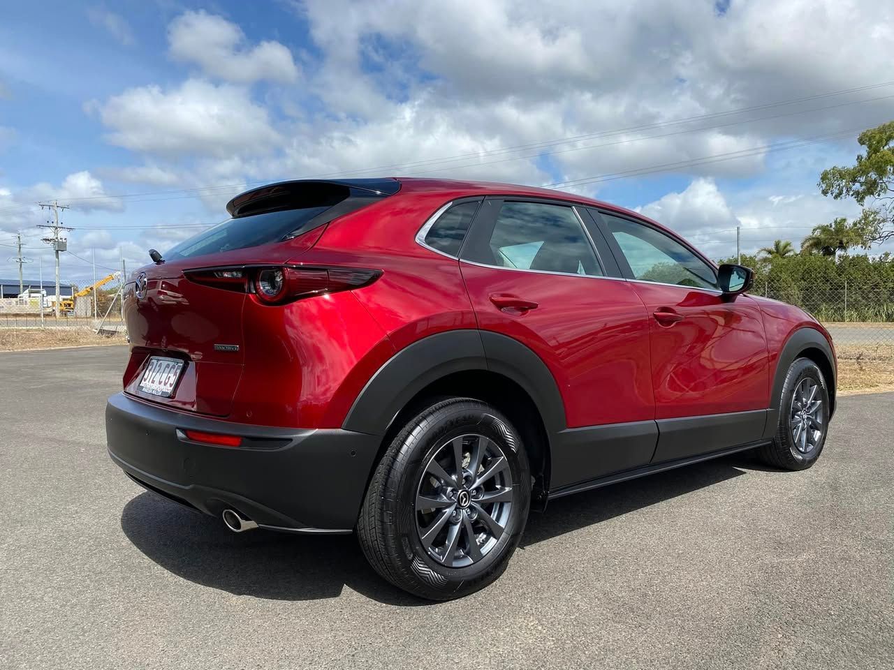 Red compact SUV in a parking lot, shown from the rear three-quarter view under a cloudy sky — Beclean Auto Detailing in Mareeba, QLD