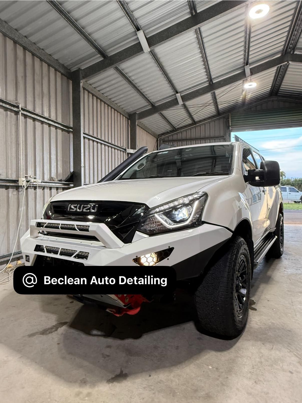 White Isuzu SUV in a detailing bay with a 