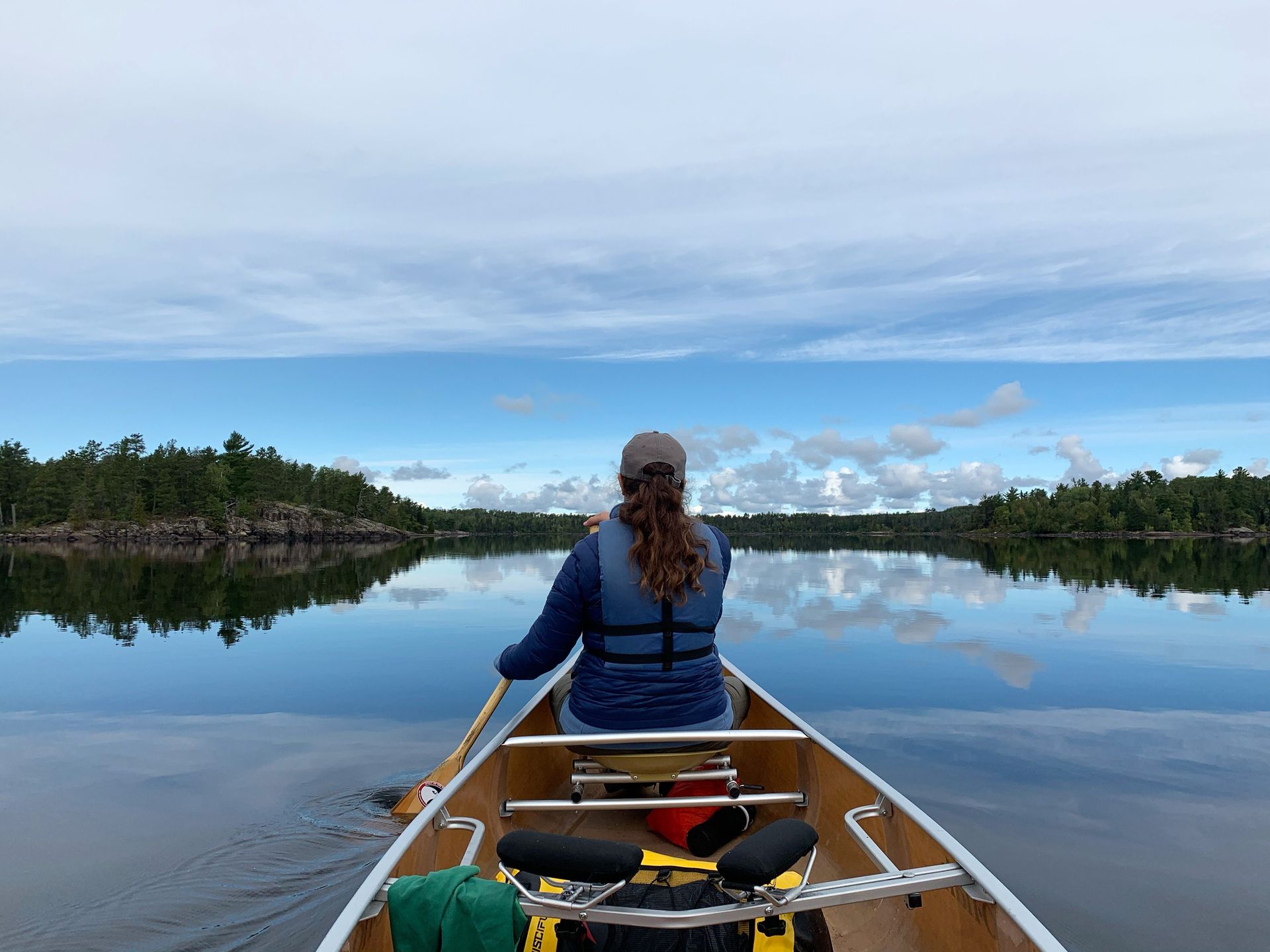 A woman is sitting in a canoe on a lake.