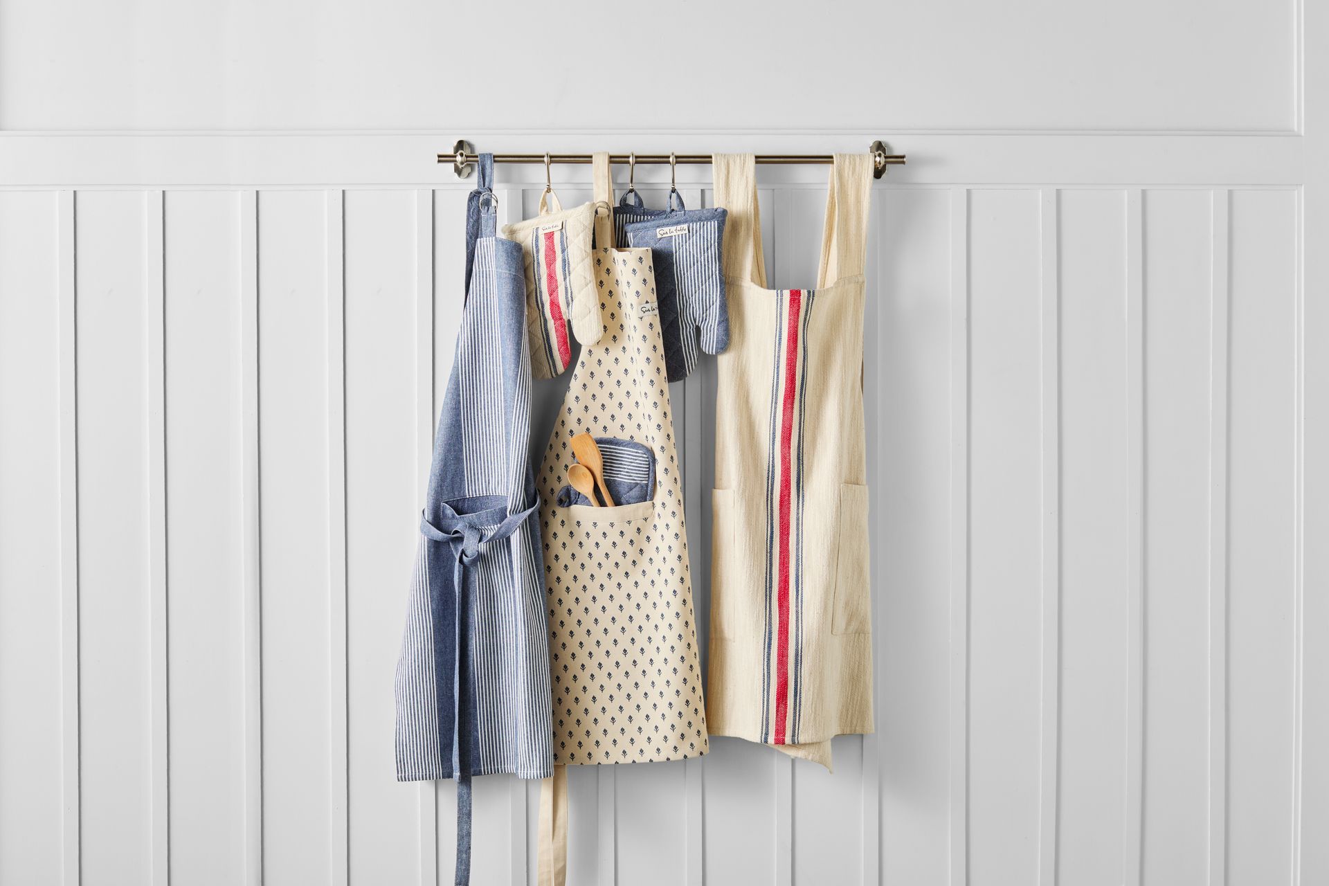 Three aprons are hanging on a rack on a wall.