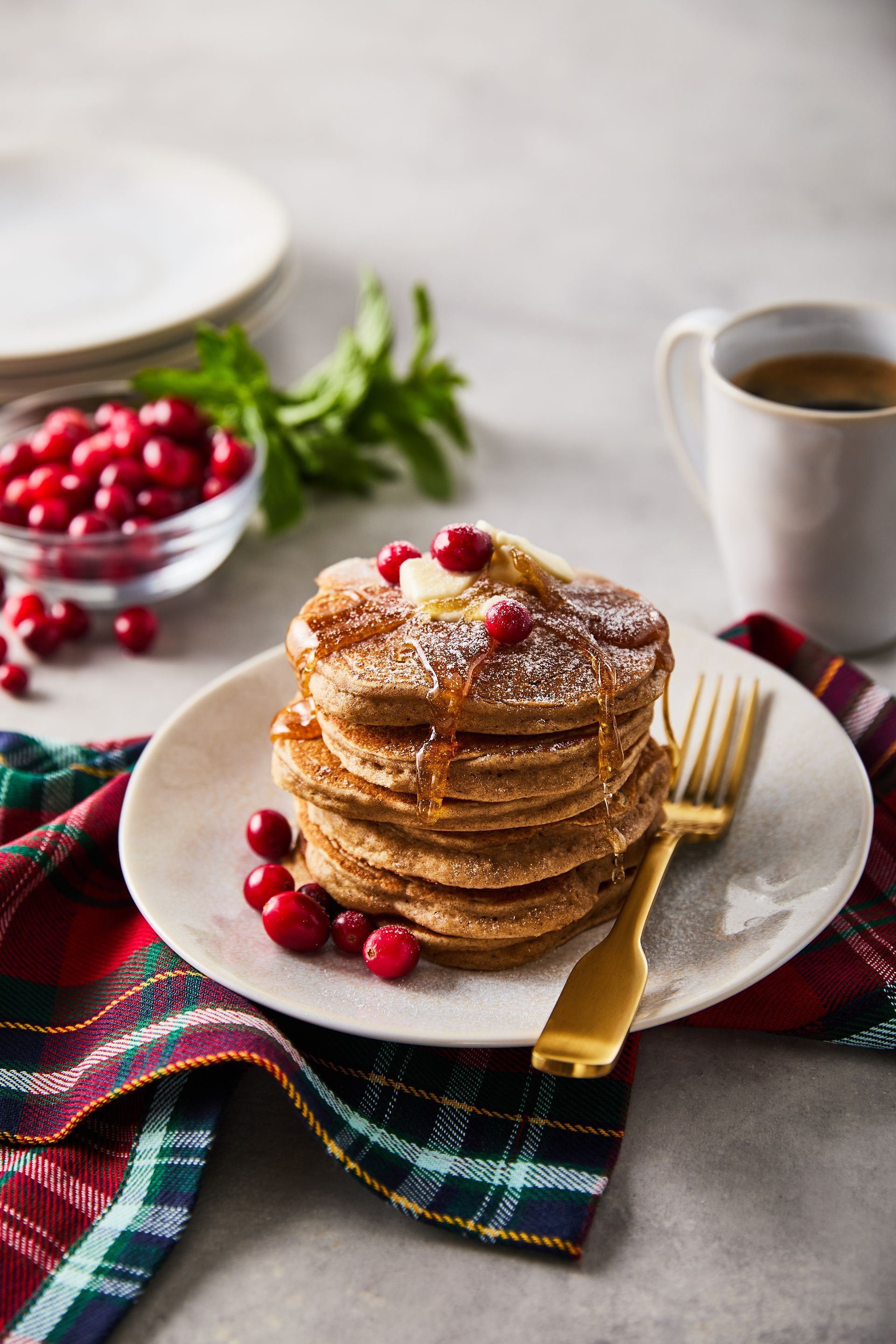 A stack of pancakes with cranberries on a plate with a fork.