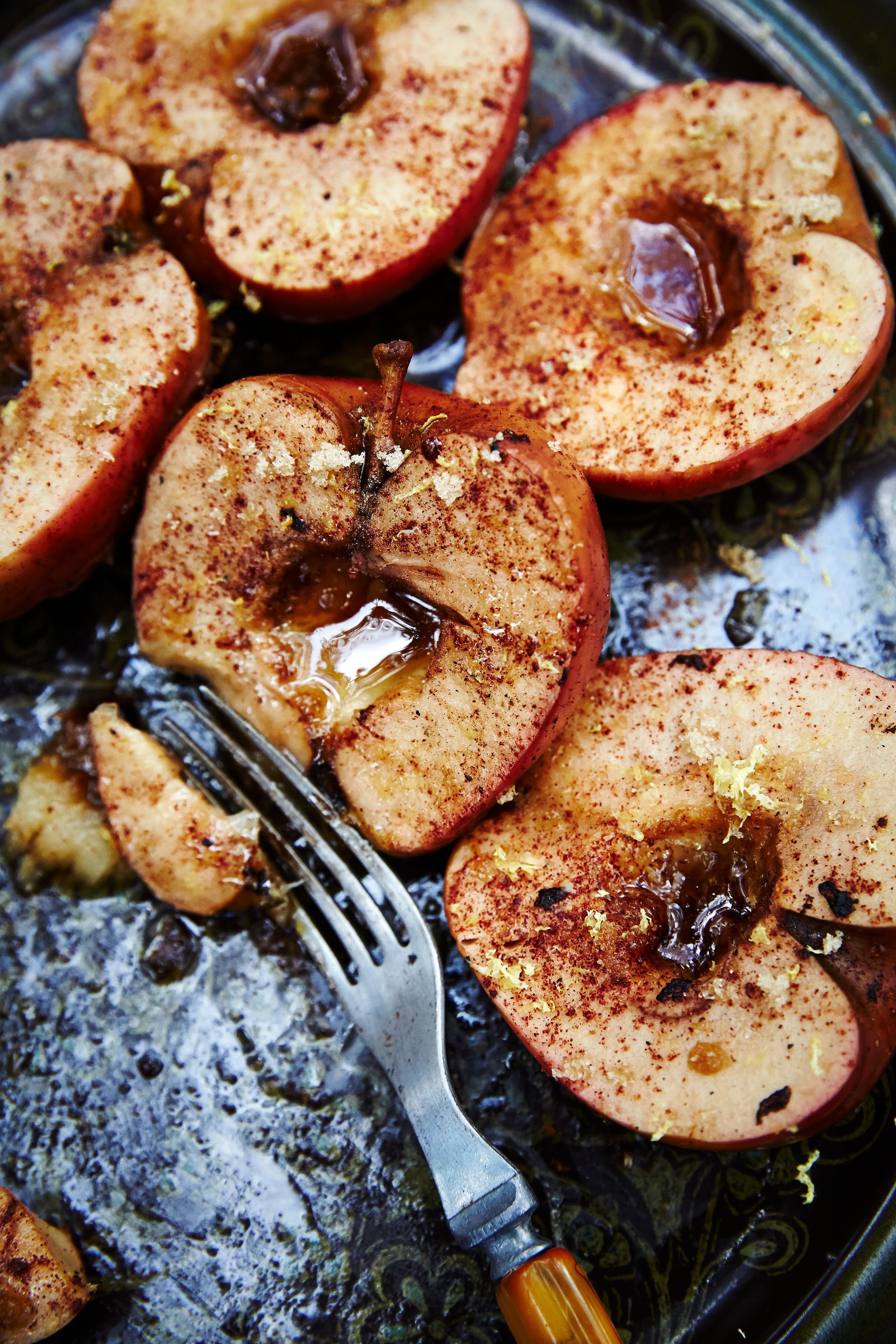 A plate of grilled sliced cinnamon apples with a fork on it.